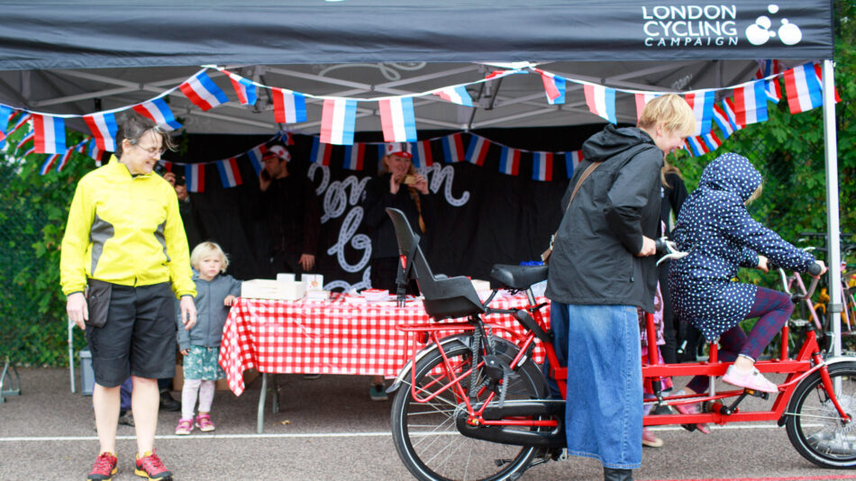 A young cyclist tries out a tandem bike in front of an LCC tent at a London Bike event.
