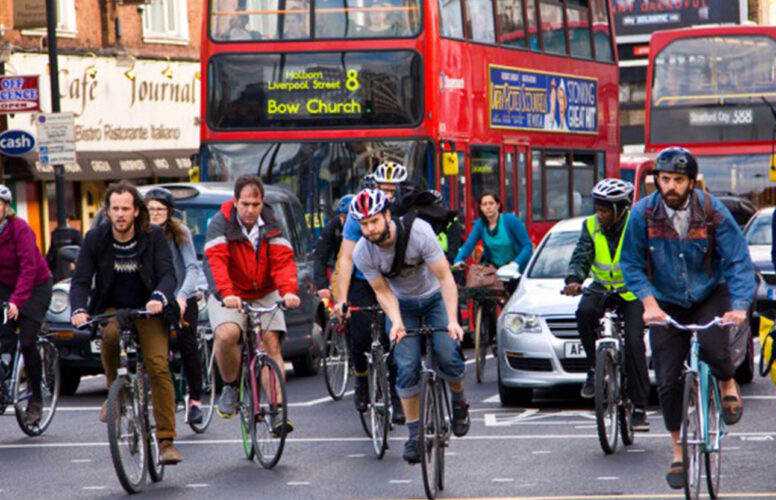 People cycling through traffic, commuters in front of cars and buses