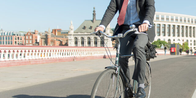 A man in a suit cycling South across Blackfriars Bridge