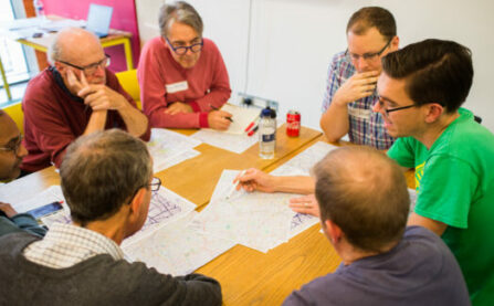 A group sitting around a table and discussing a map of cycle routes at the LCC AGM
