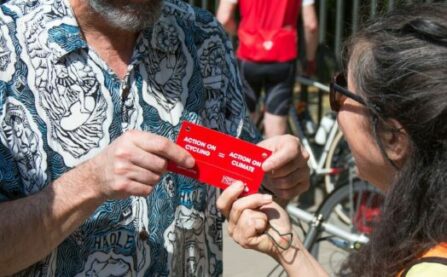 LCC man handing card to woman saying action on climate