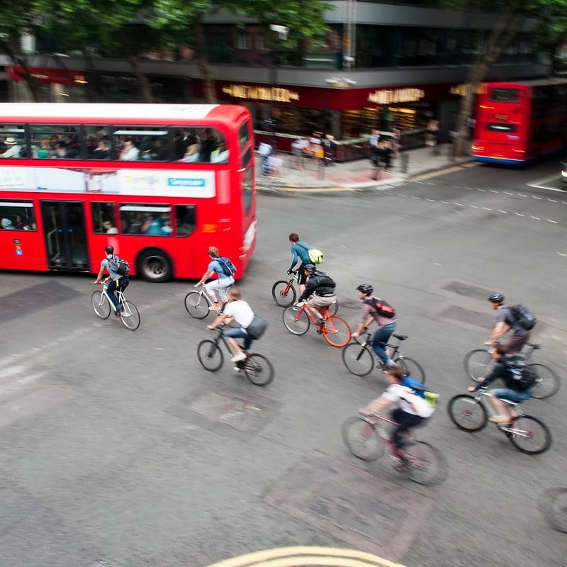 People cycling across junction with bus