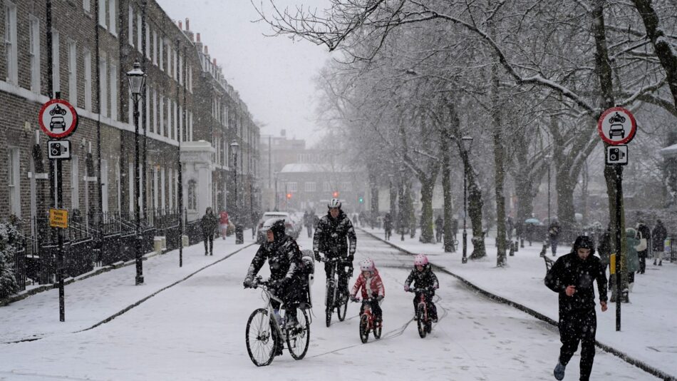 Children and parents - family cycling in the snow in Low Traffic Neighbourhood (LTN)