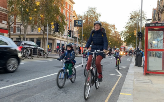 A mother and three children cycling in the Kensington High Street cycle lane