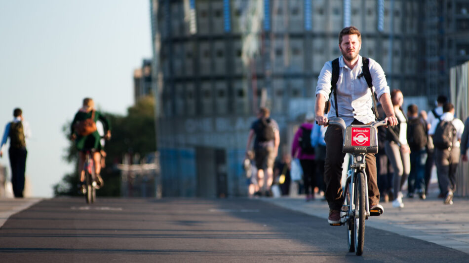 A man in work clothes cycles across Blackfriars Bridge on CS6.