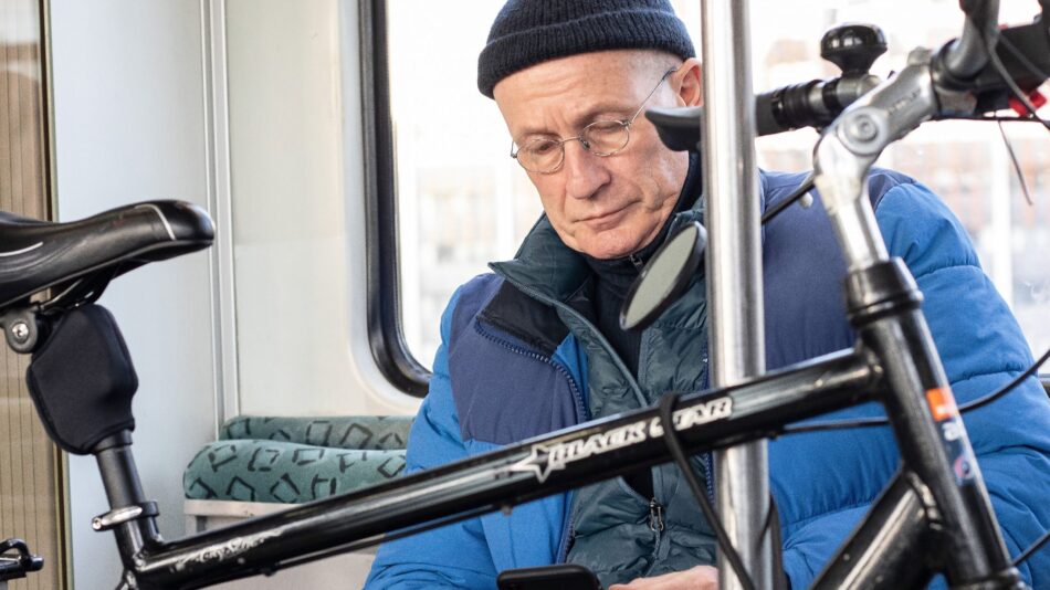 A man looking at his phone while taking a bike on public transport