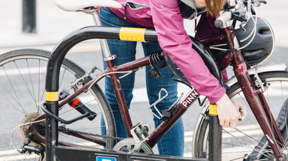 Woman parking bike to stand with lock