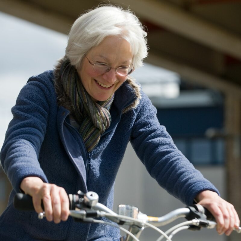 Older woman cycling and looking happy
