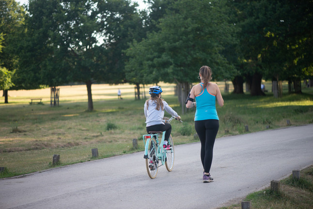 A jogger and a child on a bike in Richmond Park
