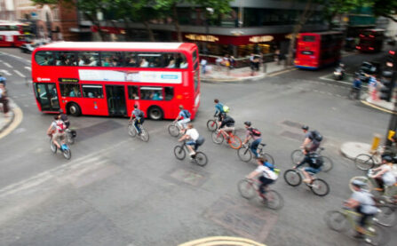 Group of people cycling through junction with bus