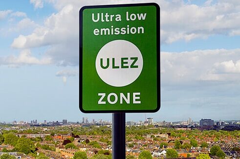 Green ultra low emissions zone sign in front of a landscape view