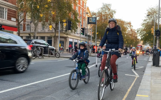 Parent with child cycling in Kensington High Street cycle lane