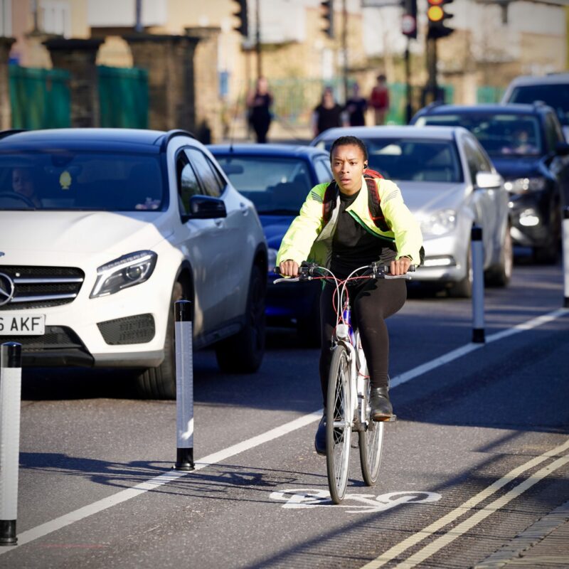 Woman cycling on wand protected lane next to traffic