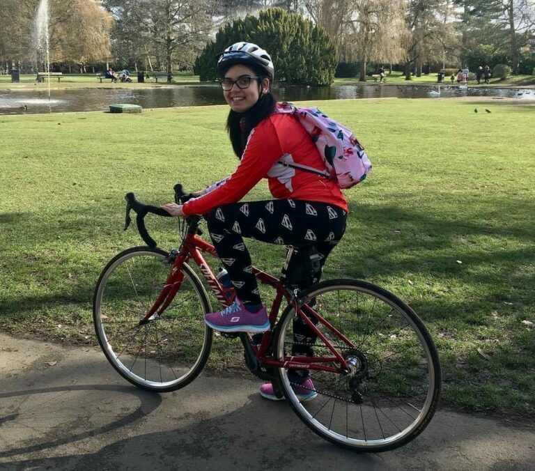 CSS Champion Katherine on her red roadbike with a white bicycle helmet, pink backpack, red long sleeve top