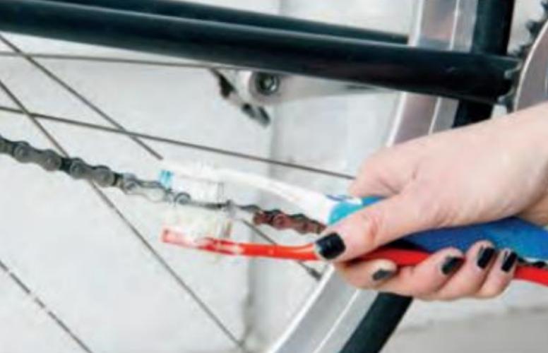 Woman bike mechanic cleaning bike chain