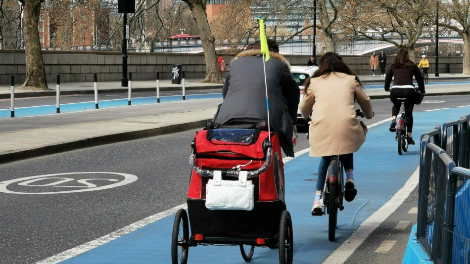 Man with bike and trailer cycling in cycle lane with wands