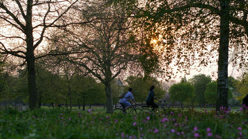 People cycling through park with sunshine