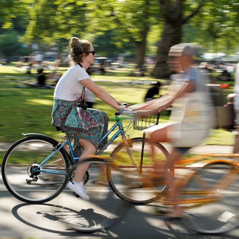 Woman on yellow bike cycling through park in sunshine