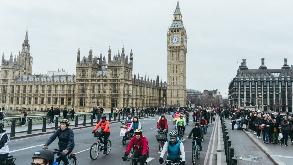 Woman cycling with big group of women over Westminster Bridge at protest ride
