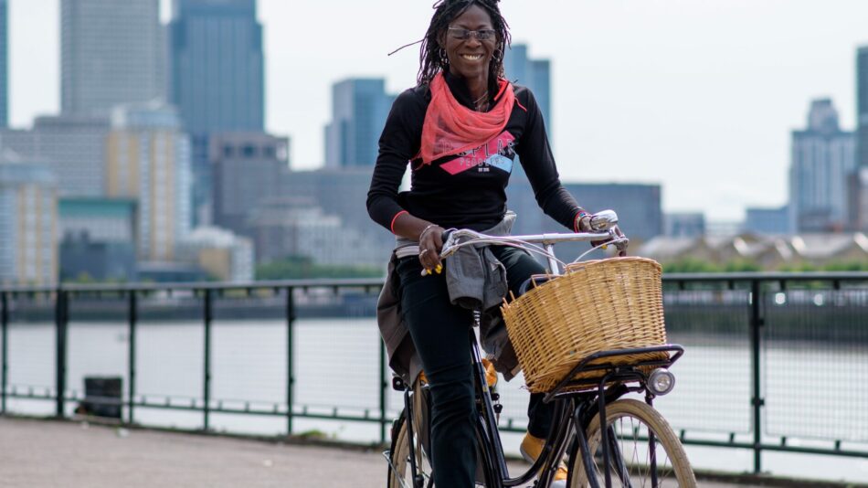 Women cycling Dutch bike with basket by river